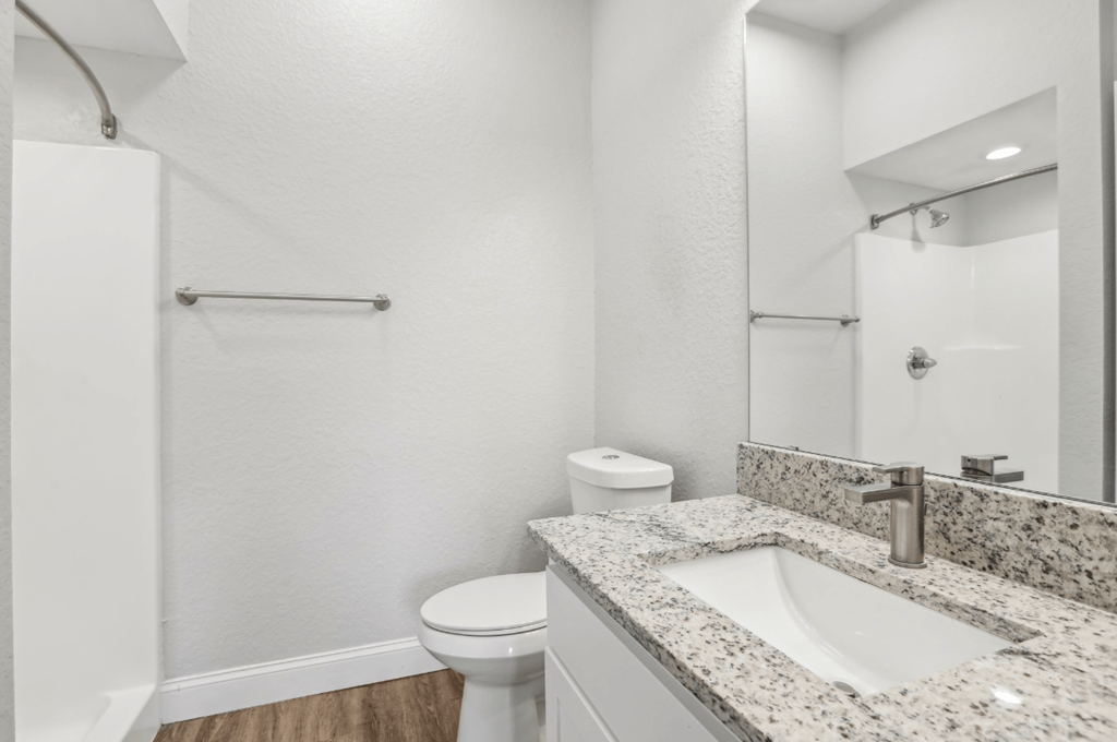 A bathroom with a toilet, sink, and mirror.